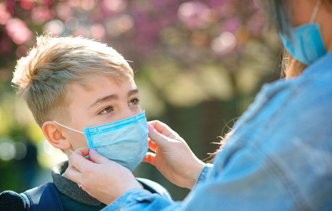 Junge mit Mundmaske schütz sich vor der Grippe