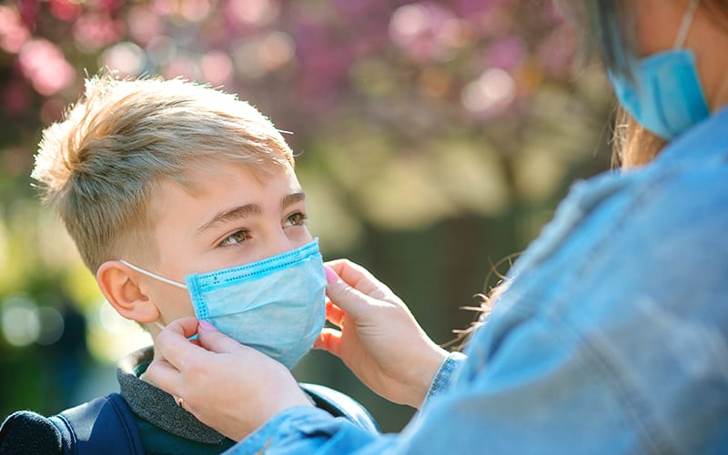 Junge mit Mundmaske schütz sich vor der Grippe